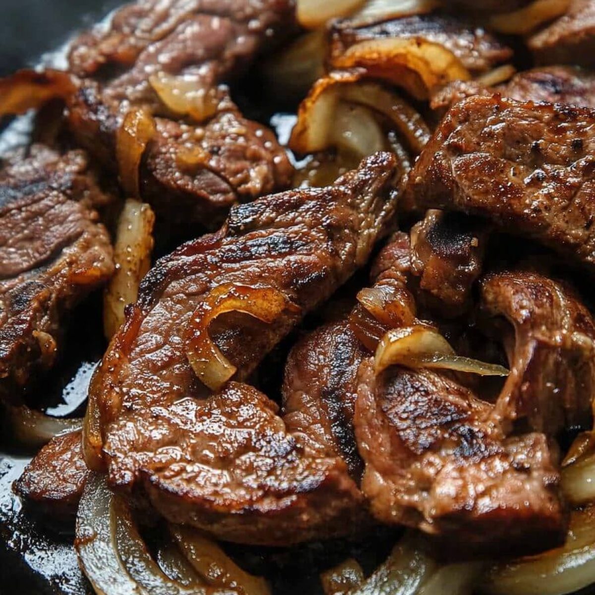 Pan-fried beef liver with caramelized onions in a skillet
