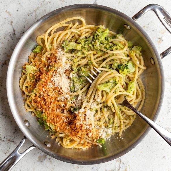 Overhead view of garlic broccoli spaghetti with Parmesan and toasted panko in a skillet