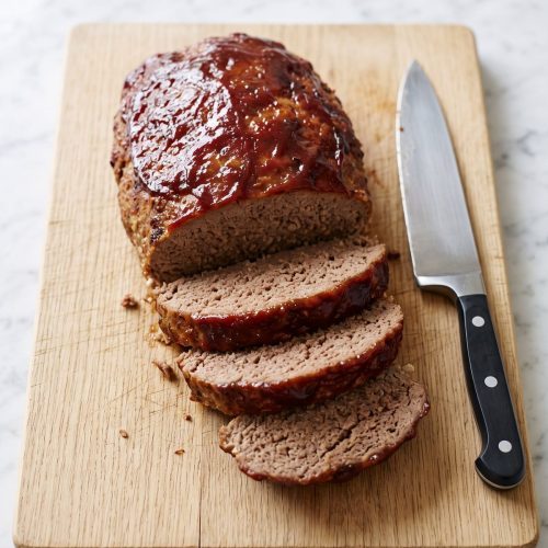 A glazed air fryer meatloaf on a cutting board with the front end cut into thick slices