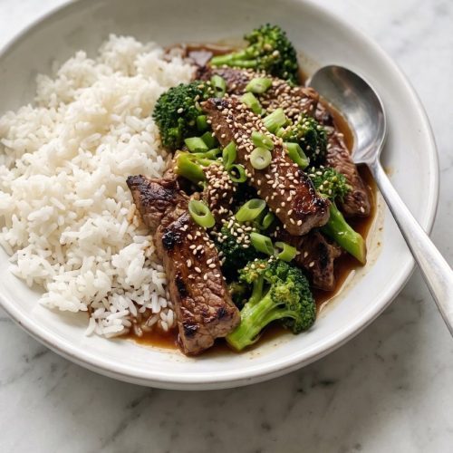 Beef and broccoli teriyaki over white rice in a wide bowl, topped with sesame seeds