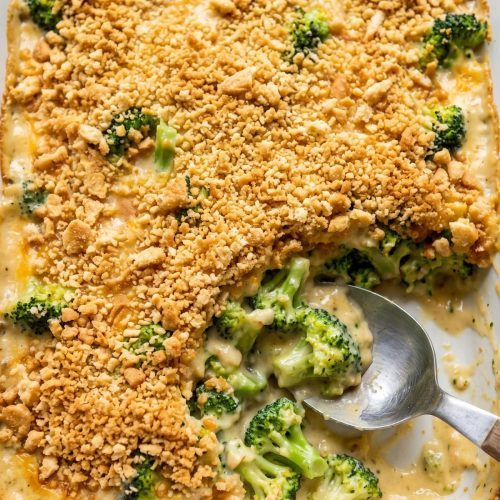 Broccoli casserole with a golden buttery cracker topping in a white 9x13 dish, one corner scooped out