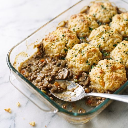 Cheddar biscuit casserole with a portion scooped out to show the creamy ground-beef and vegetable filling