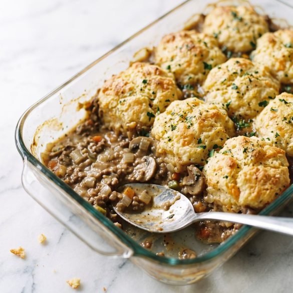 Cheddar biscuit casserole with a portion scooped out to show the creamy ground-beef and vegetable filling