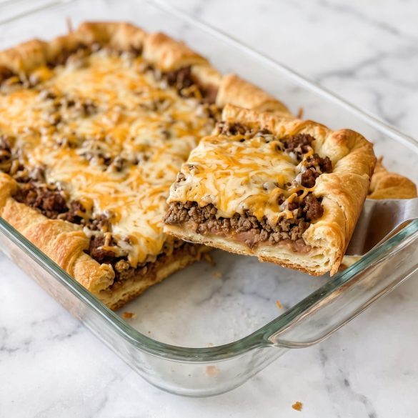 A sliced crescent roll taco bake showing its beef, bean, cheese, and crescent dough layers.