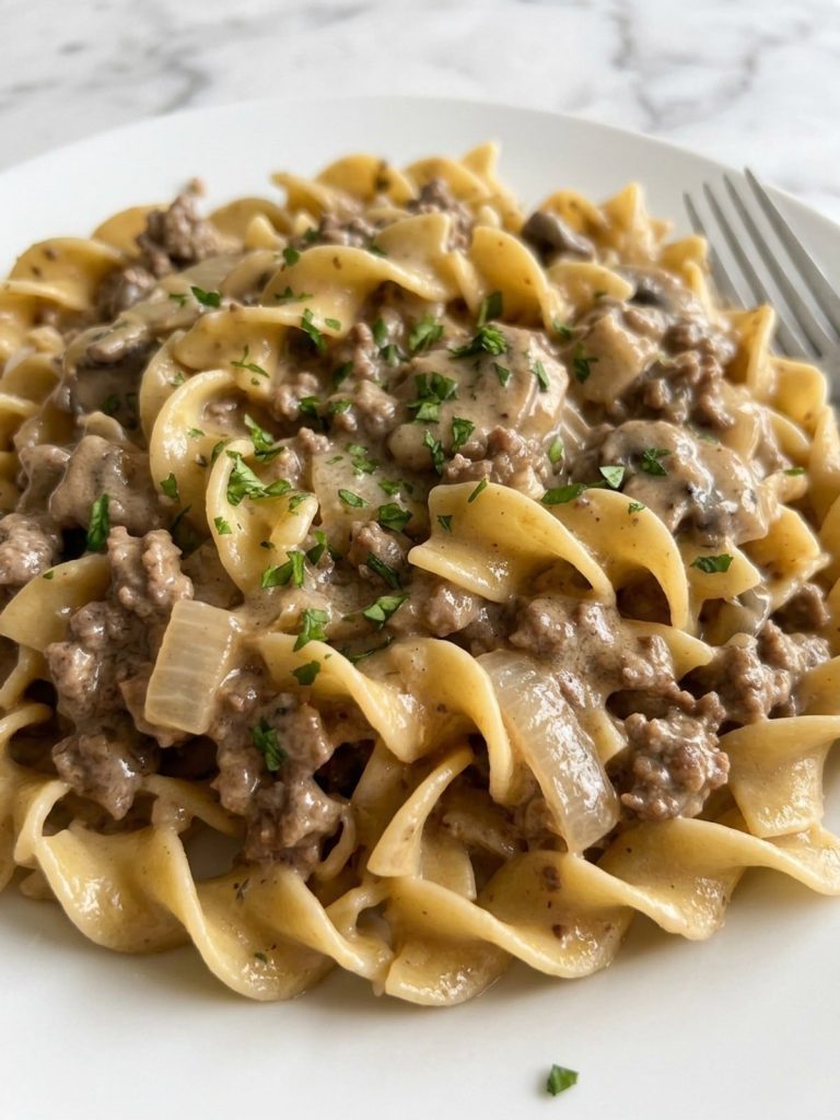 Close view of a forkful of egg noodles in creamy ground beef stroganoff sauce