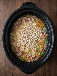 Step 2: Dry Great Northern beans, diced ham and vegetables sit in water in the slow cooker.