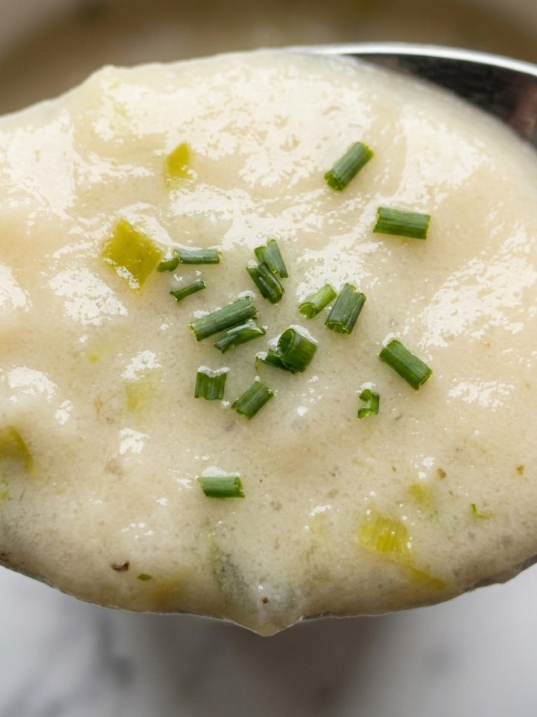Close view of a spoonful of smooth, creamy potato leek soup with chives
