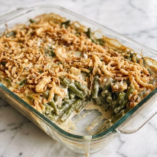 Green bean casserole with creamy beans and crisp fried onions scooped from a baking dish