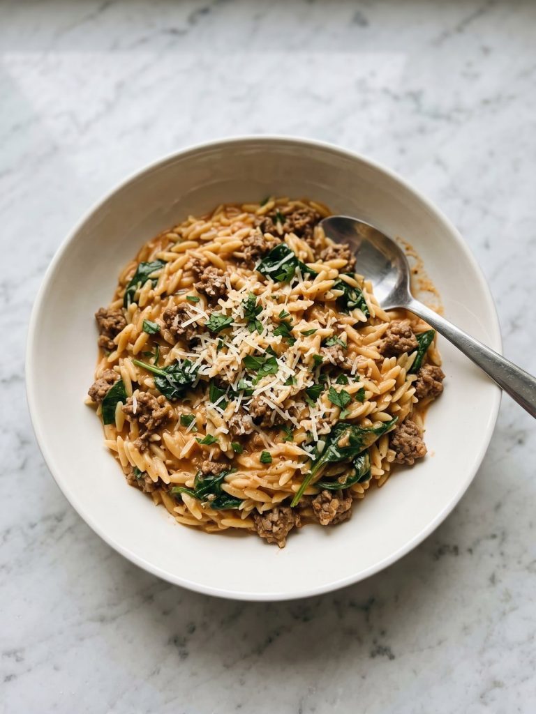 Creamy ground beef orzo with spinach and parmesan in a wide white bowl
