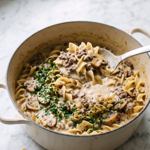 Ground beef stroganoff with mushrooms and egg noodles scooped from a Dutch oven