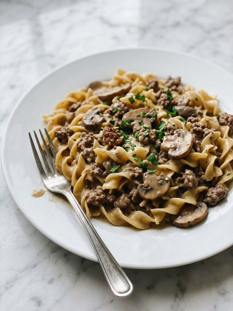 Close view of a plate of creamy egg noodles with ground beef and mushrooms