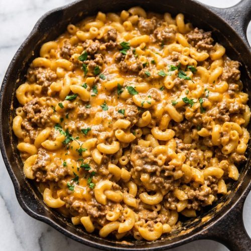 A skillet of creamy cheeseburger macaroni with ground beef and melted cheddar