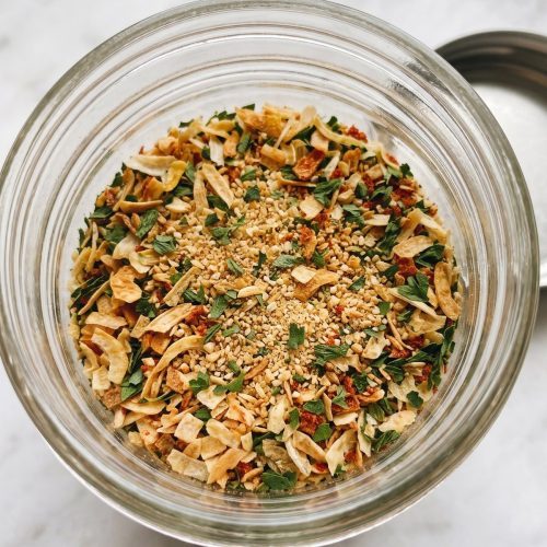 A glass jar of homemade dry onion soup mix with onion flakes and herbs