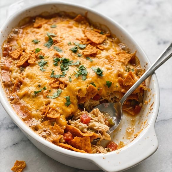 Cheesy chicken and Doritos casserole in a baking dish with a serving scooped out