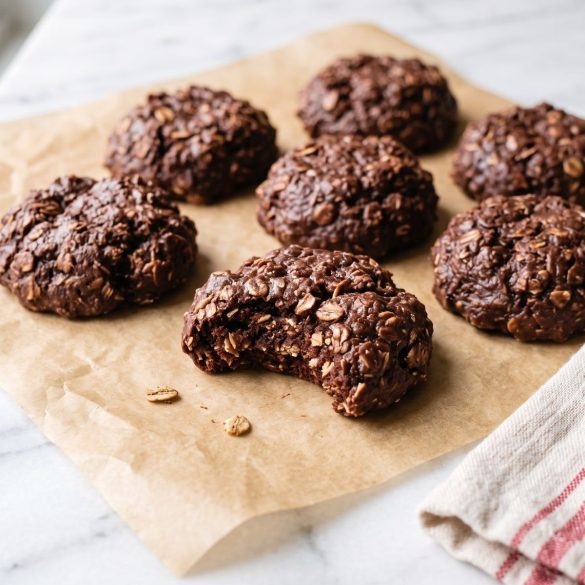 Set chocolate oatmeal cookies on parchment, with one broken open to show its fudgy oat-filled center.
