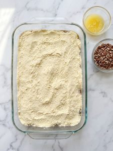 Step 4: An even layer of dry yellow cake mix completely covers the pecan filling in the baking dish.