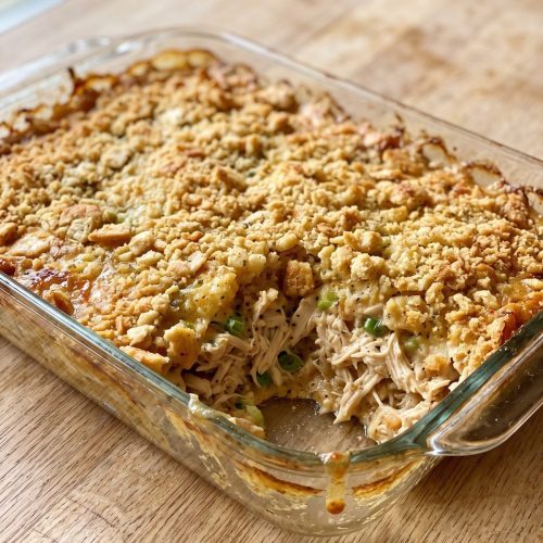 Ritz cracker chicken casserole with a portion scooped out to show the creamy shredded chicken beneath the golden topping.