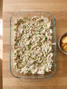 Step 2: Creamy shredded chicken filling spread evenly in a glass baking dish.