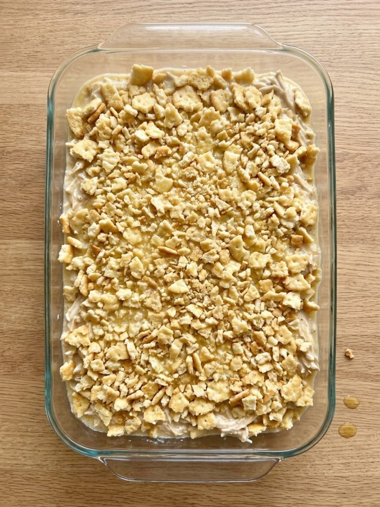 Step 5: Creamy chicken filling covered evenly with butter-coated Ritz cracker pieces before baking.