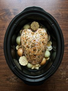 Step 3: Butter-rubbed turkey breast sits skin-side up on onion and garlic in the slow cooker.