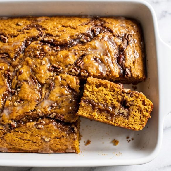 A 9x13 pan of glazed sweet potato honey bun cake with a brown sugar swirl