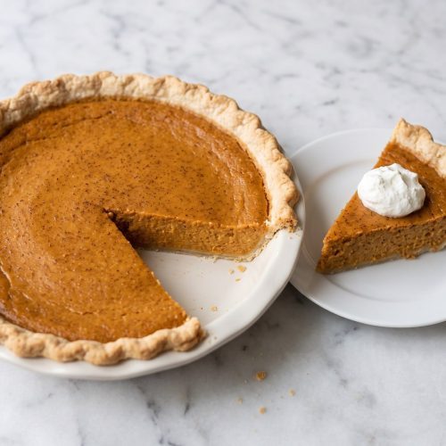 Sweet potato pie with one slice removed to show the creamy filling and golden crust.