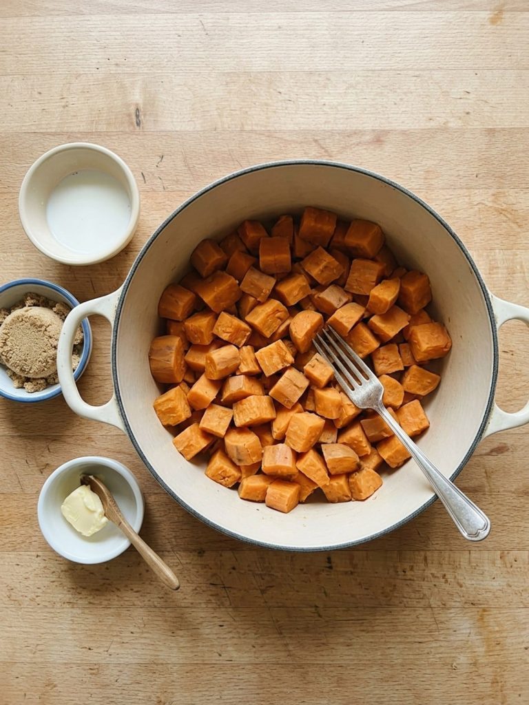 Step 2: Fork-tender sweet potato cubes sit drained in a pot, cooling before they are mashed.