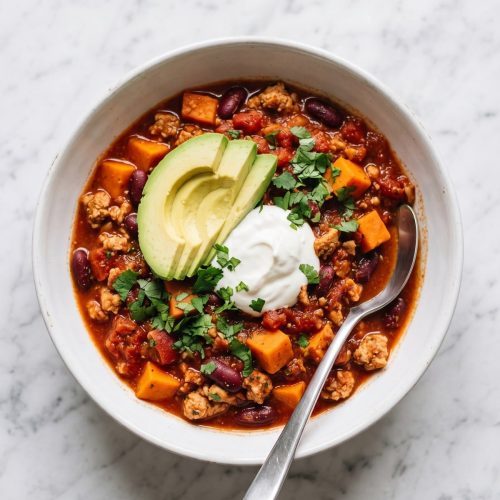 A bowl of turkey sweet potato chili with kidney beans, avocado and cilantro