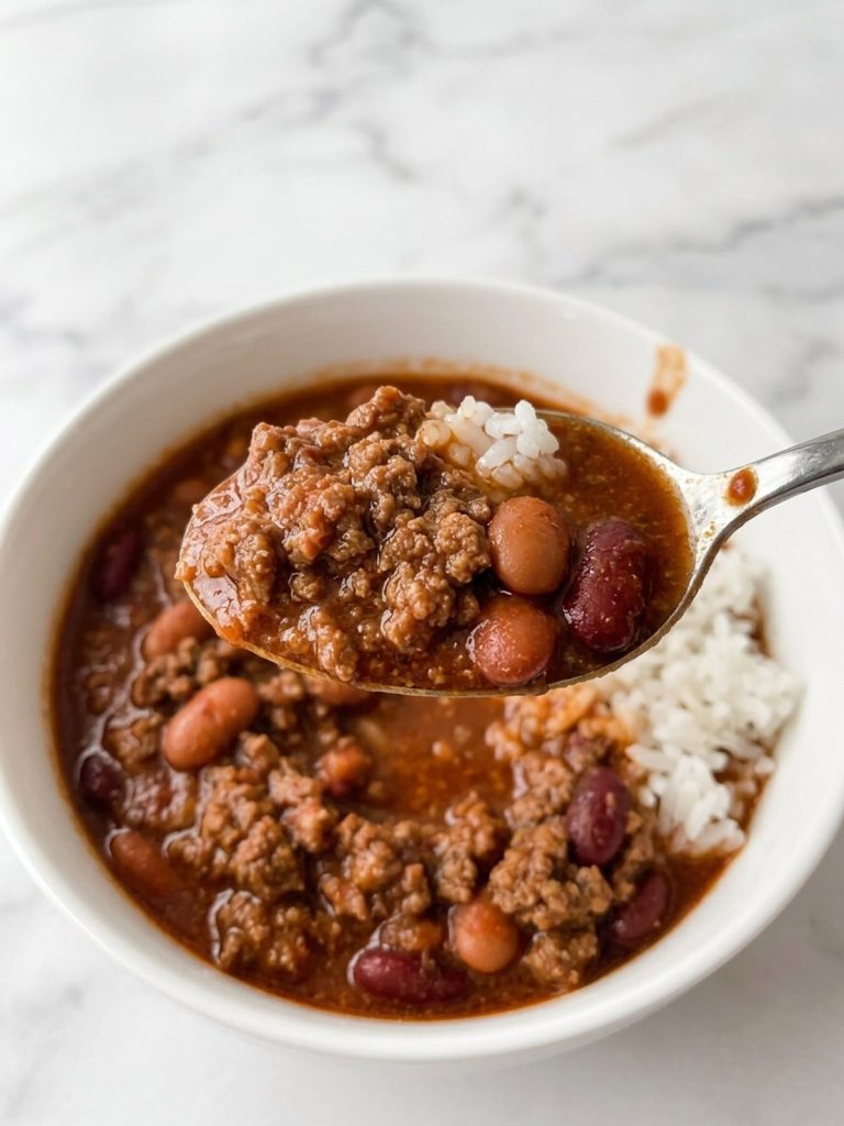 Close view of a spoonful of thick chili and white rice