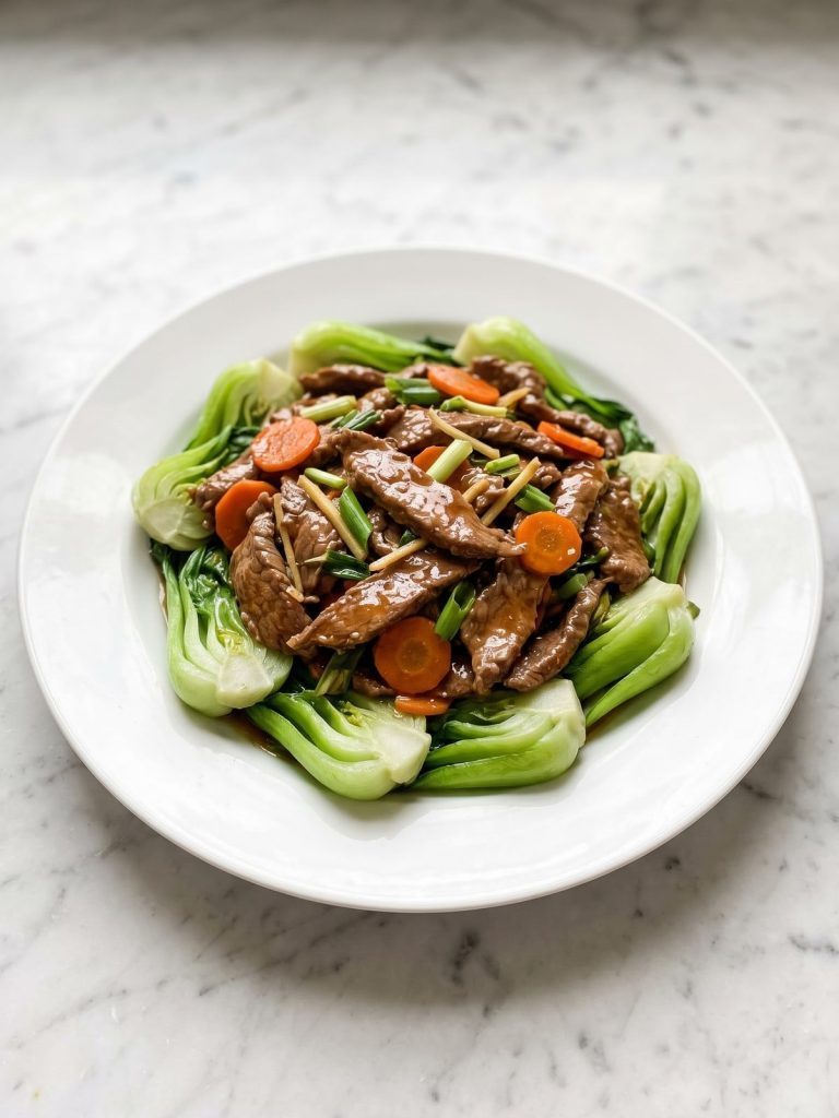 Beef and bok choy stir fry with glossy sauce on a white plate