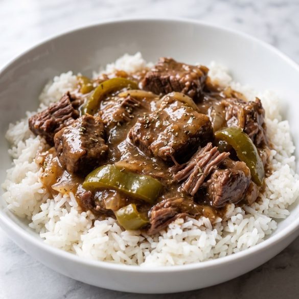 A bowl of white rice topped with tender beef stew, sliced green peppers and onions in a thick brown gravy
