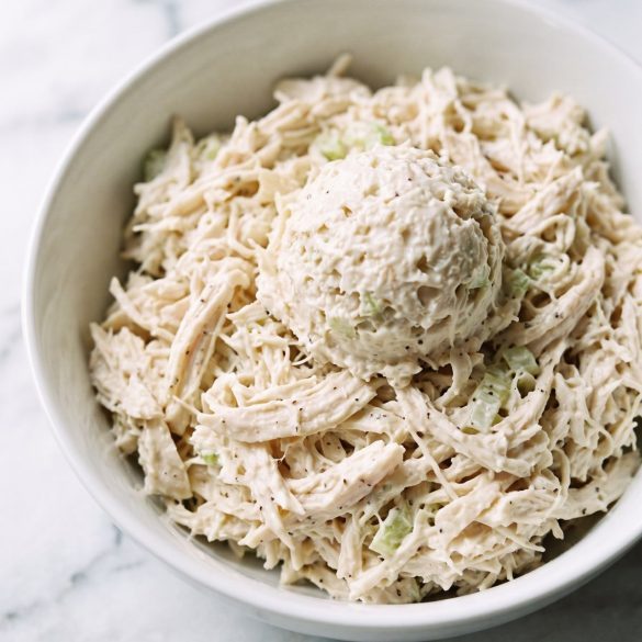 A scoop of finely shredded, creamy chicken salad in a white bowl