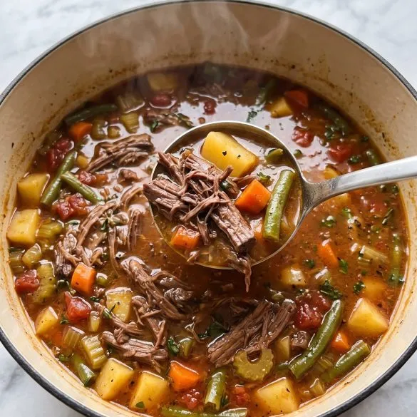 A Dutch oven of vegetable beef soup with shredded chuck roast, potatoes, carrots and green beans