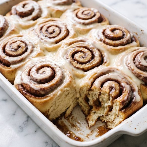 A pan of large gooey cinnamon rolls covered in thick cream cheese icing