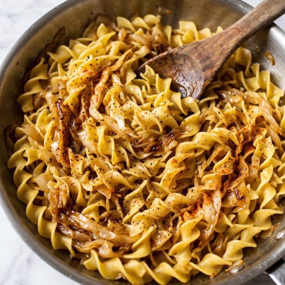 A large skillet of egg noodles tossed with golden caramelized cabbage