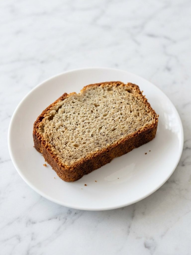 A thick slice of moist banana bread on a white plate