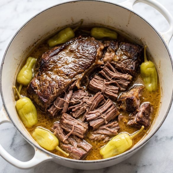 Shredded Mississippi pot roast with pepperoncini peppers and gravy in a Dutch oven