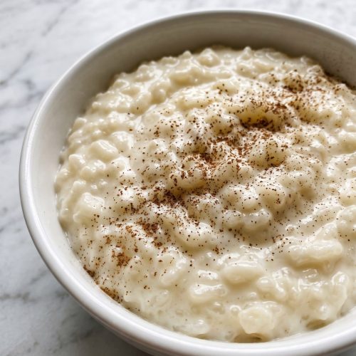 A white bowl of creamy old fashioned rice pudding dusted with cinnamon