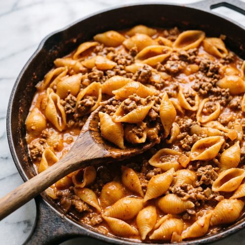 A skillet of medium pasta shells and ground beef in a creamy tomato sauce
