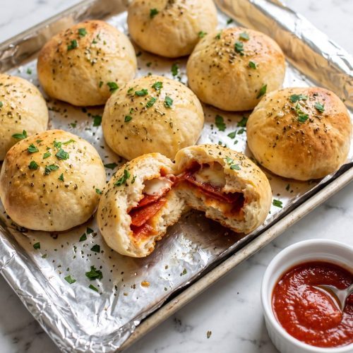 Golden pizza balls brushed with garlic butter, one torn open to show pepperoni and melted mozzarella