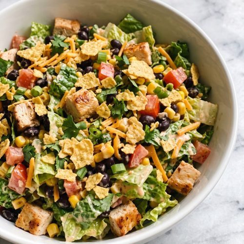 A large bowl of Tex-Mex chopped chicken salad with romaine, black beans, corn, tomatoes and tortilla chips