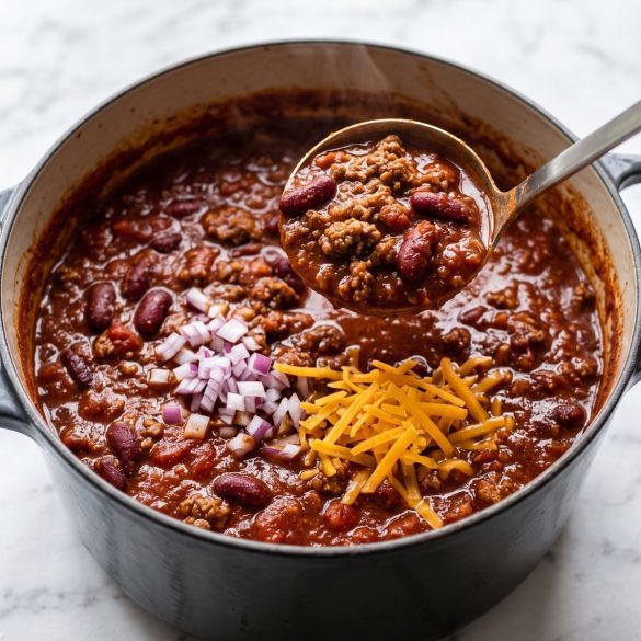 A pot of thick ground beef and kidney bean chili with a ladle