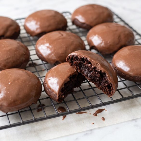 Chocolate cookies covered in glossy cooked chocolate frosting on a cooling rack