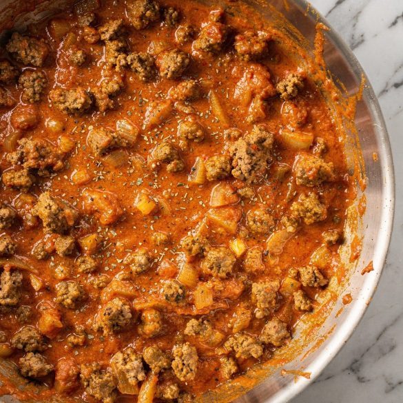 A skillet of smooth red tomato meat sauce with ground beef and onion
