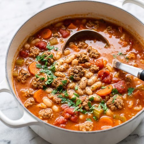 A Dutch oven of white bean and Italian sausage soup with carrots, celery and tomatoes